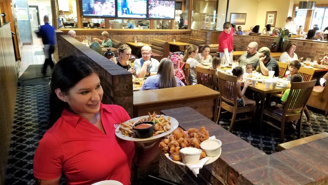 Server Susan Doss delivers fried mushrooms and cheese fries to a table in Rafferty's on Green River Rd.