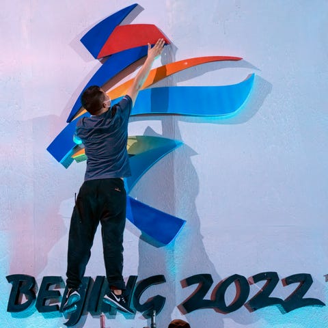 A crew member leaps to fix a logo for the 2022 Bei