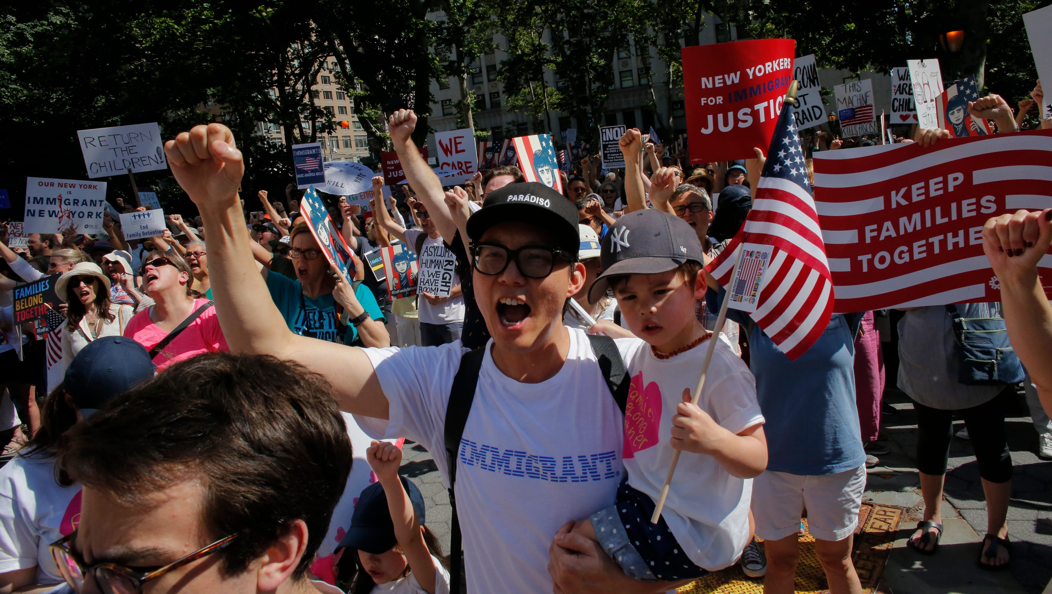 People cheer as they attend the Families Belong Together