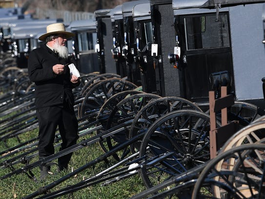 An Amish man looks over one of the many buggies offered up for auction during a mud sale in Gordonville, Pa., on Saturday, March 10, 2018. The annual event, which helps raise money for volunteer fire companies, offers indoor and outdoor auctions, selling items from buggies and farm equipment to horses.