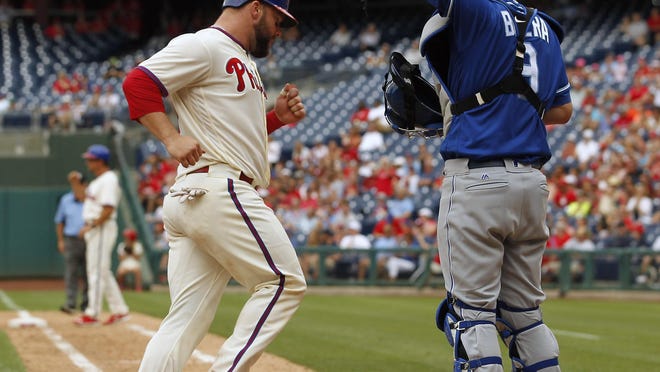 Philadelphia’s Cameron Rupp crosses the plate in front of Kansas City’s Drew Butera during the eighth inning Sunday,in Philadelphia. The Phillies won 7-2.