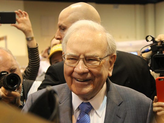 Warren Buffett smiling and speaking with reporters.