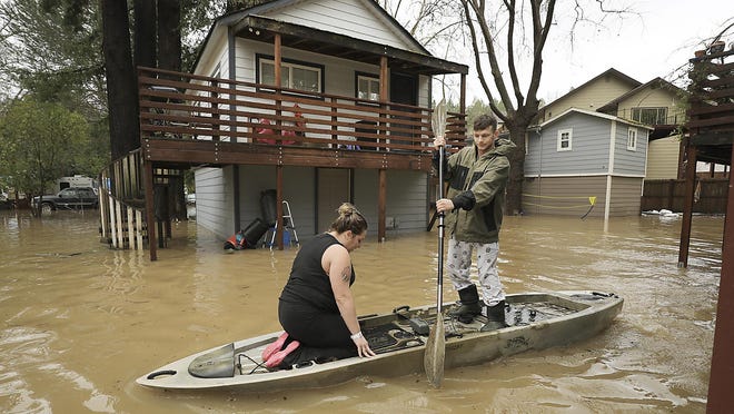 Residents of Sycamore Court flooded by Armstrong Creek, who declined to give their names, paddle out of high water from their apartment in Guerneville, Calif., Feb. 14, 2019. Waves of heavy rain pounded California on Thursday, trapping people in floodwaters, washing away a mountain highway, triggering a mudslide that destroyed homes and forcing residents to flee communities scorched by wildfires last year.