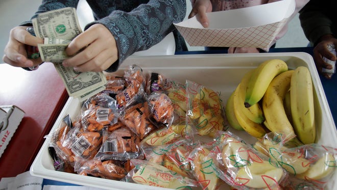 In this file photo, a student at Fairmeadow Elementary School pays for lunch consisting of fruits and vegetables during a school lunch program in Palo Alto.