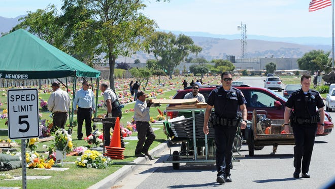 Salinas police officers return from searching the scene around the funeral Thursday of Heron Moran. Shots may have been fired into the air around the ceremony at Garden of Memories in Salinas.