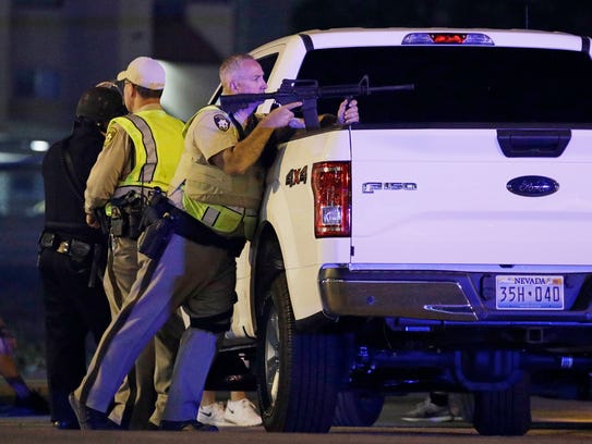A police officer takes cover behind a truck at the