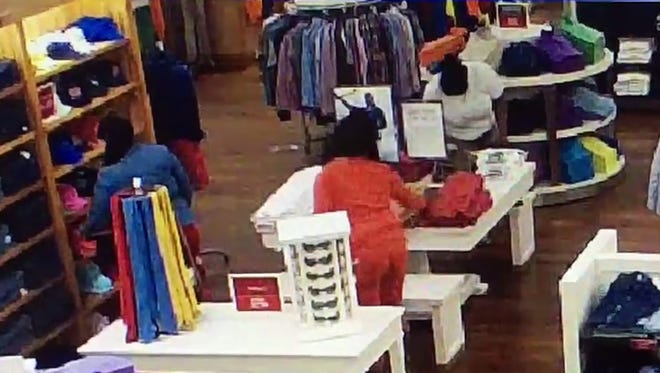Still from surveillance video from a Polo Ralph Lauren store showing three women filling bags with merchandise.