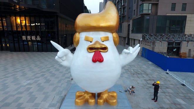 A worker takes a picture of a giant rooster sculpture resembling U.S. President-elect Donald Trump on display outside a shopping mall to celebrate the upcoming Chinese Year of the Rooster in Taiyuan in north China's Shanxi province. (Chinatopix via AP)