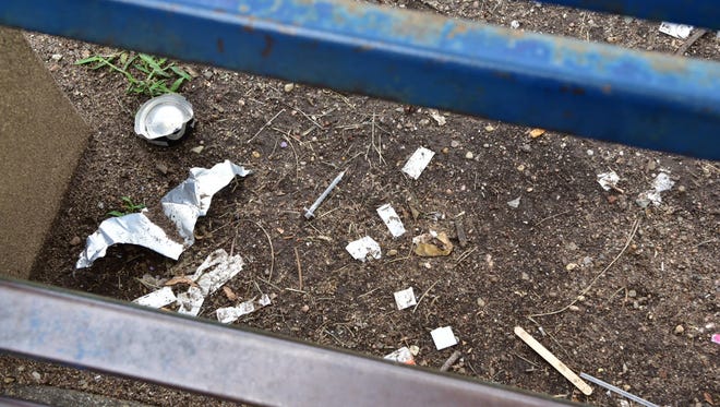 Used needles and other signs of drug use under a bench at Barbour Park in Paterson.