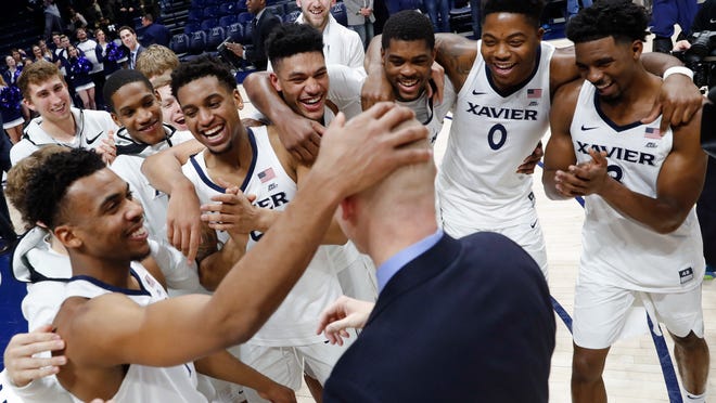 Xavier head coach Chris Mack, center, celebrates with his players after becoming the winningest coach in Xavier's history after an NCAA college basketball game against St. John's, Wednesday, Jan. 17, 2018, in Cincinnati. Xavier won 88-82. (AP Photo/John Minchillo)