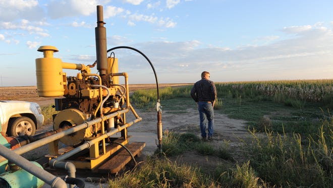 Jay Garetson looks into a cornfield next to a pump on his family's farm in southwestern Kansas. He said when he thinks about the challenges the next generation faces due to declining groundwater levels, "thats what leaves you gasping for air."
