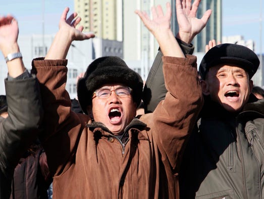 People cheer as they watch the news broadcast announcing