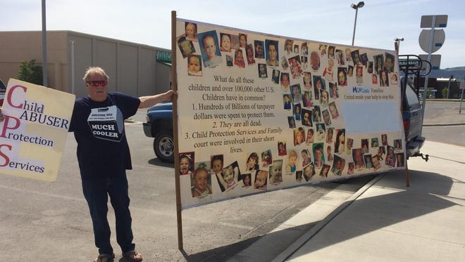 Mark Supanich participates in a rally Wednesday in Helena calling for reforms to the state’s child protective services. He is with a banner of children who have died nationwide while under the care of child protective services.