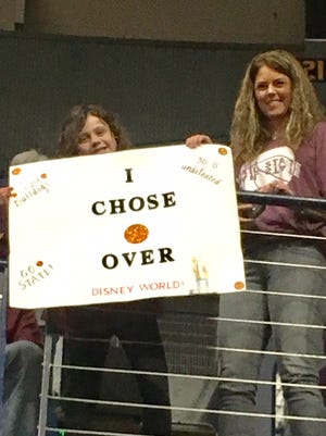 Seven-year-old Kennedy Laine Harper, left, displays a poster saying that she chose an SEC tournament trip over Disney World. Harper, standing beside her mother, is from Brandon, Miss.