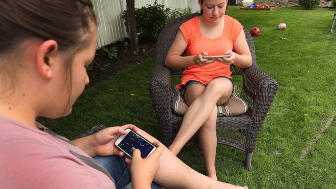 Morgan Selleneit, right, and her friend Macee Silvester on their cell phones at a home in Centerville on Thursday, May 31, 2018.