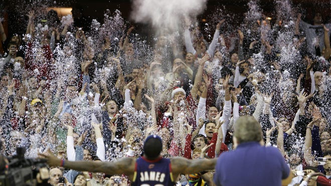 In this Dec. 25, 2008, file photo, fans toss confetti to mimic Cleveland Cavaliers' LeBron James's pre-game chalk toss before an NBA basketball game against the Washington Wizards in Cleveland.