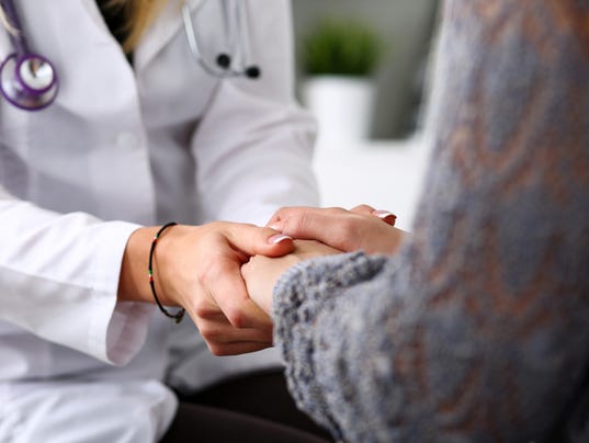 Friendly female doctor hold patient hand in office during recept