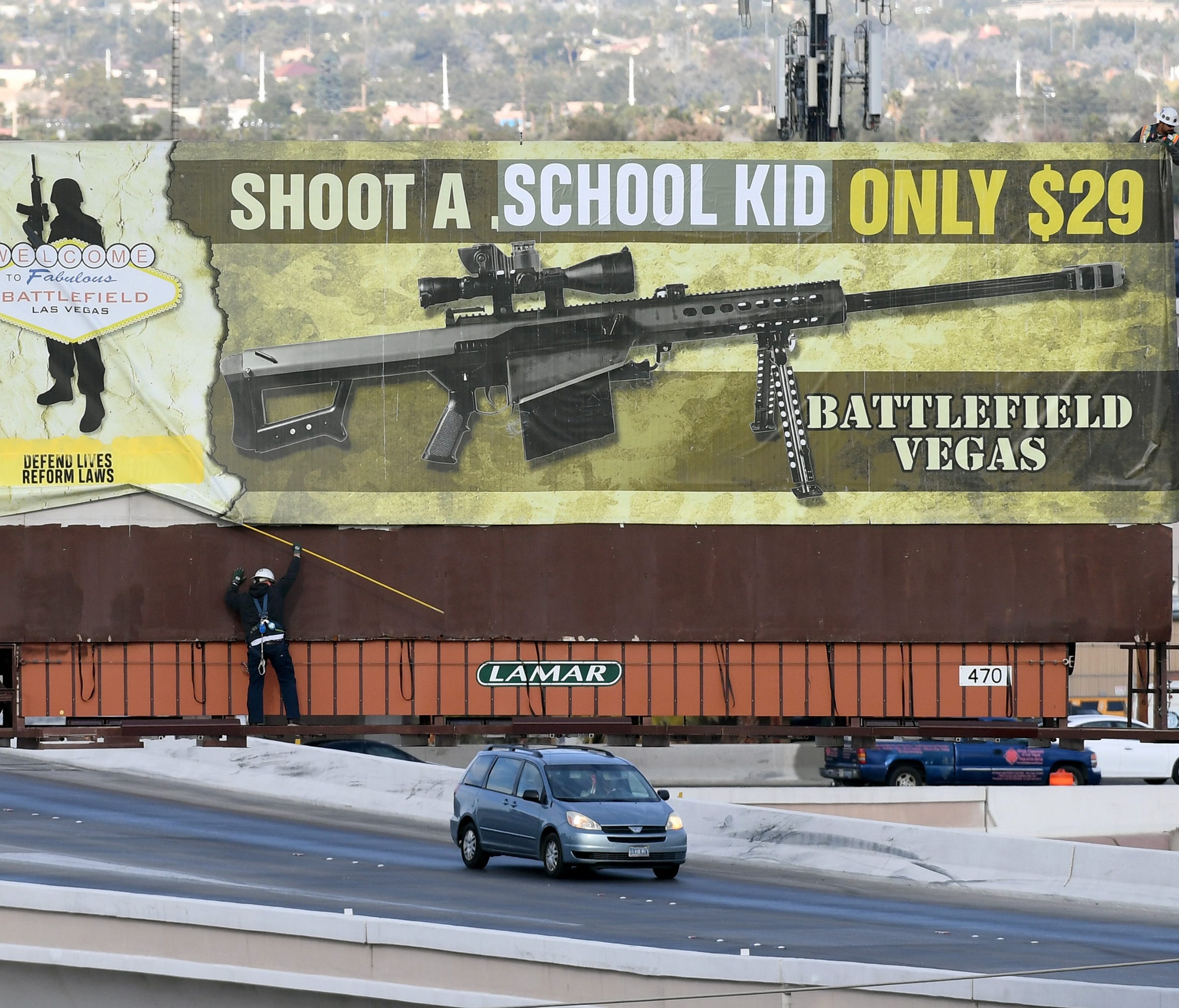 Workers are pictured removing a billboard poster for the Battlefield Vegas shooting range after it was vandalized.