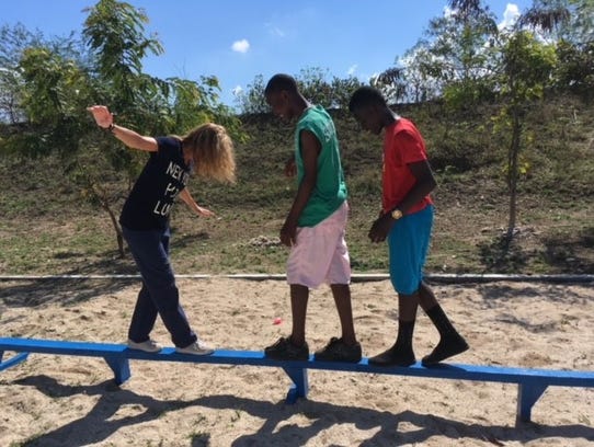 Jill Engel walks the balance beam with two Haitian