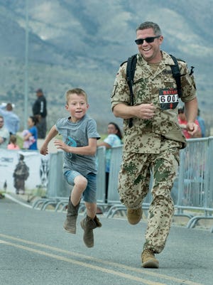 Stephan Plambeck from El Paso, is joined by his son Fredrick, 7, for the sprint to the finish line of the 29th Bataan Memorial Death March held Sunday, March 25, 2018, at White Sands Missile Range.