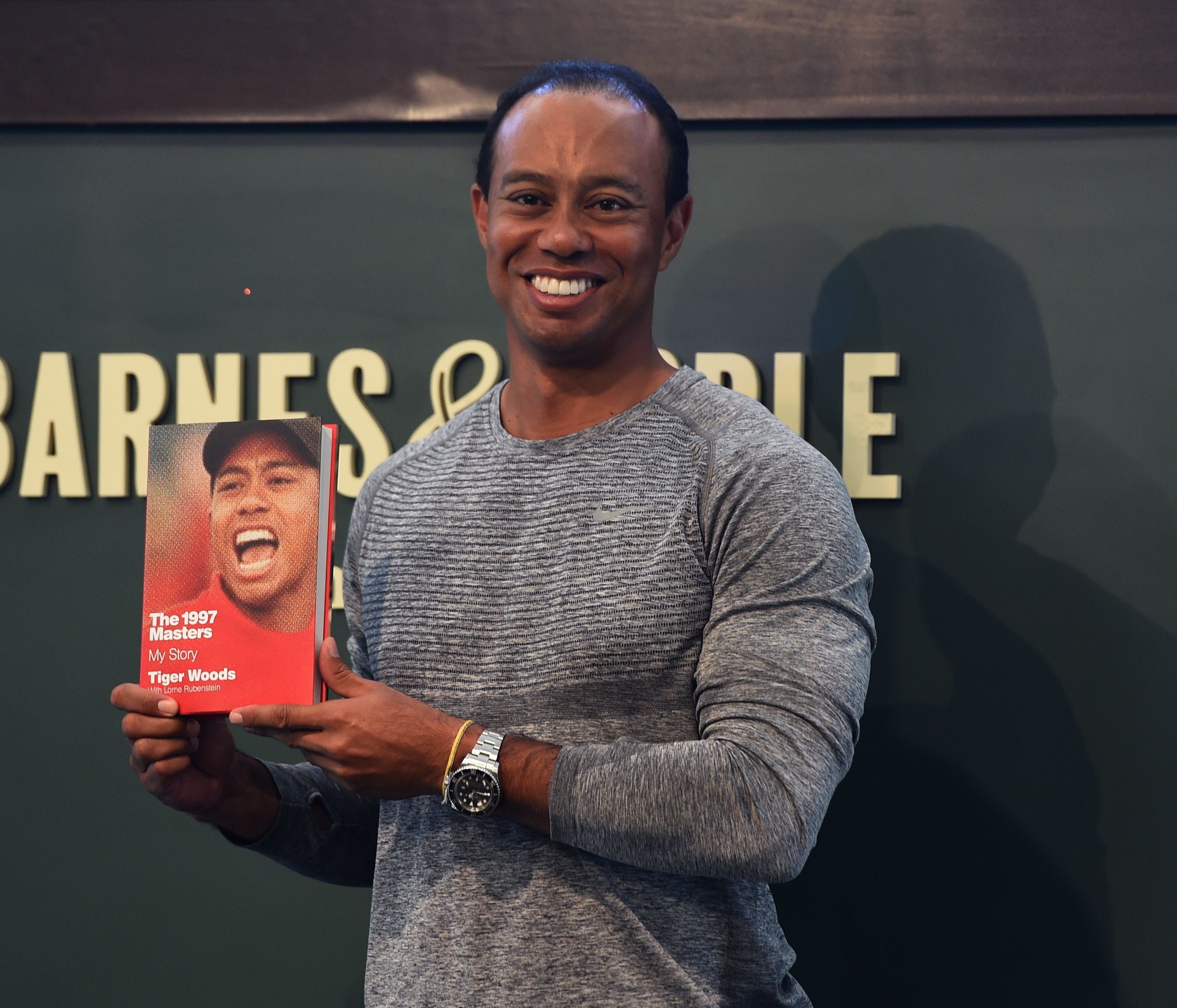 (FILES) This file photo taken on March 20, 2017 shows  14-time major champ  golfer Tiger Woods holdig a copy of his new book 
