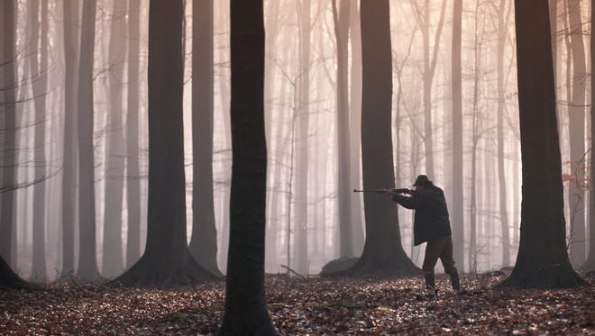 Man aiming shotgun in forest in this undated photo.
