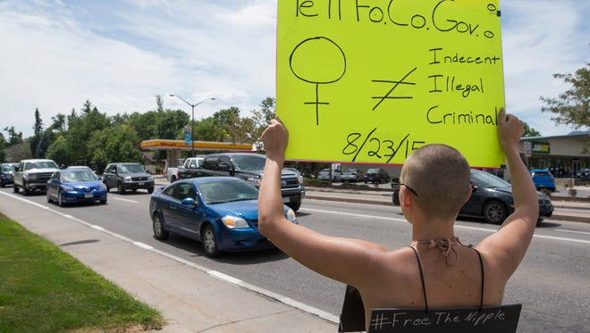 Brittiany Hoagland protests Fort Collins indecency laws as traffic passes by at the intersection of S. Shields St. and W. Elizabeth St. Thursday, August 6, 2015. Hoagland says the language in the city law is sexist and unconstitutional against women and the transgender community. 