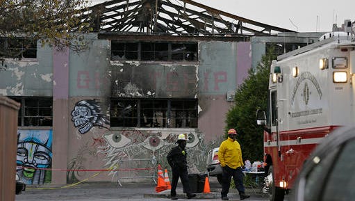 Oakland fire officials walk past the remains of the Ghost Ship warehouse damaged from a deadly fire in Oakland, Calif. The Dec. 2 fire killed dozens of people during a electronic dance party, after it raced through the building, trapping them inside. For those who survived, it was largely a matter of luck that when the first cries of “fire” were heard, they were able to find their way through smoke and darkness or were near enough to a door or already outside. (AP Photo/Eric Risberg,File)