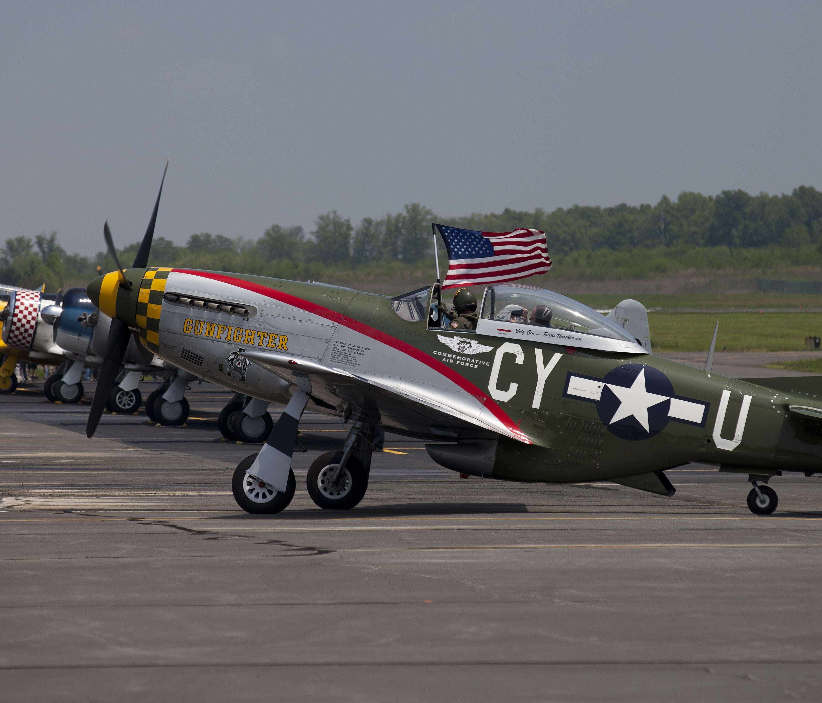 The pilot of a P-51 Mustang waves the American flag after a practice flight with dozens of World War II era aircraft at Culpeper Regional Airport in Brandy Station, Virginia, 2015.