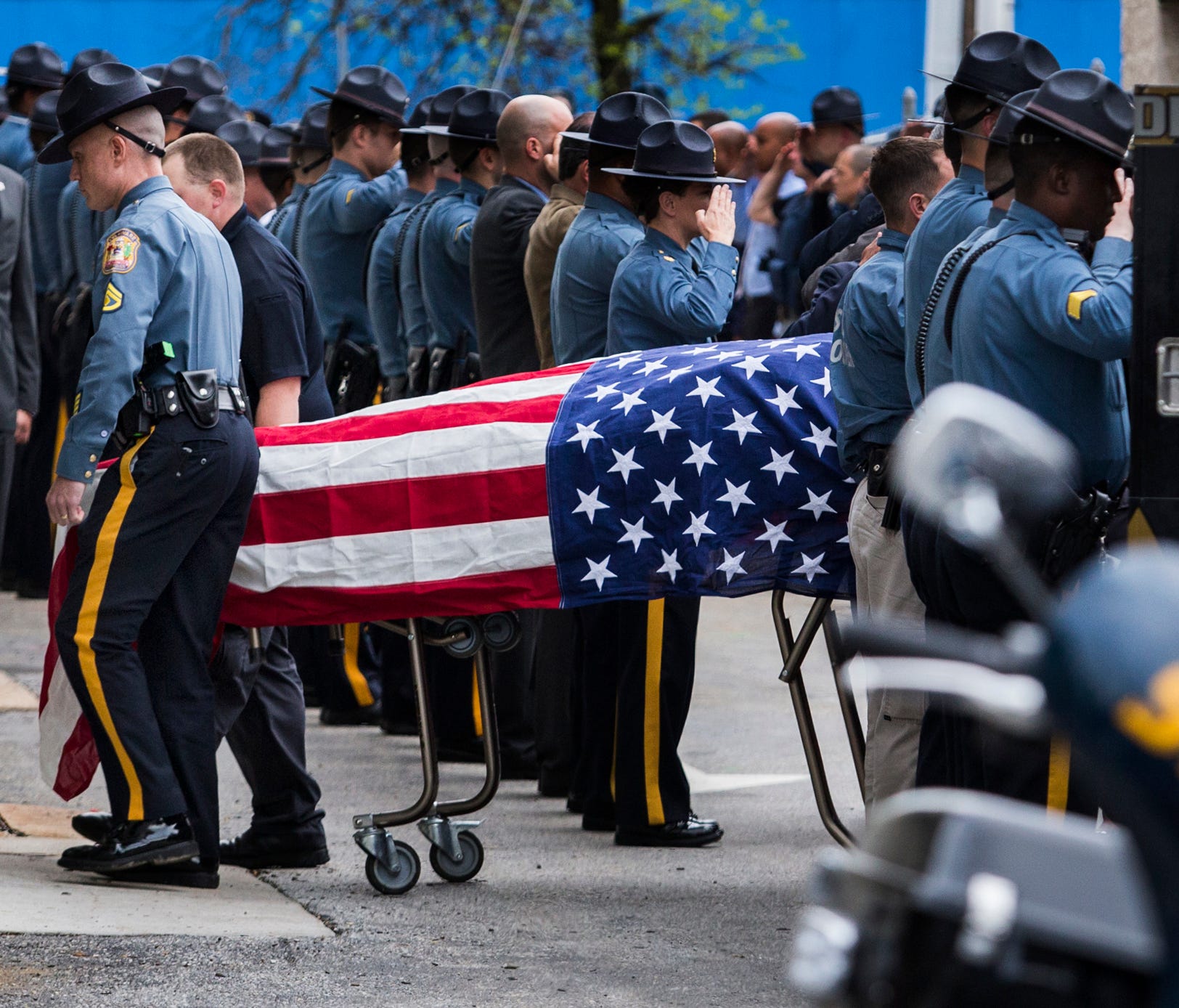 Delaware State Police officers salute as the remains of a trooper killed in the line of duty are brought into the Delaware Medical Examiner's office in Wilmington on Wednesday afternoon.