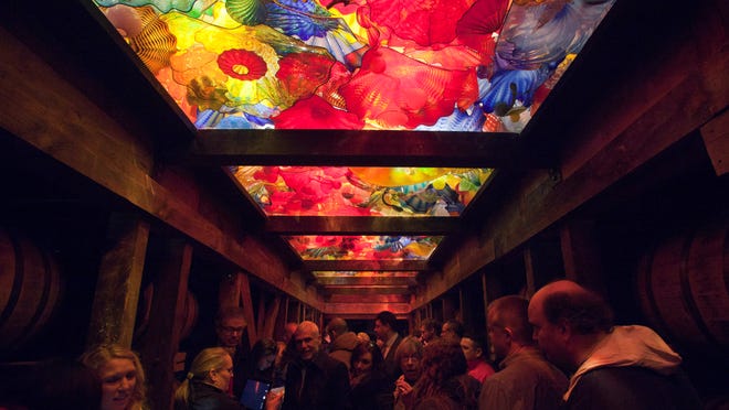 Visitors observe the various pieces of glass that compose a newly unveiled glass art installation at the Maker's Mark Distillery.