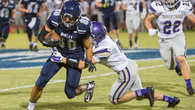 Queen Creek’s Travis Moore (right) tackles Higley’s Trent Gilbert during their game on Sept. 26, 2014, in Gilbert.