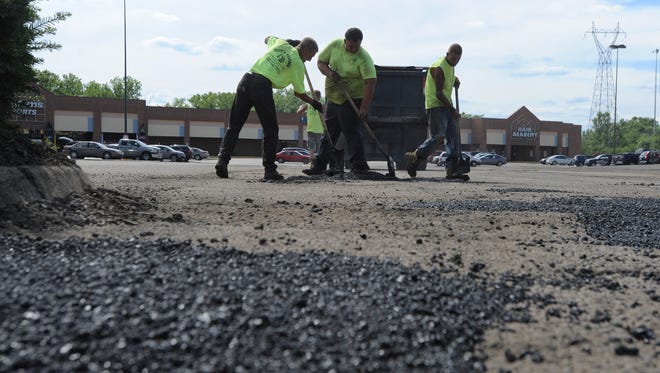 A crew from Gus's Paving fills potholes Thursday in the parking lot of Shawnee Square.