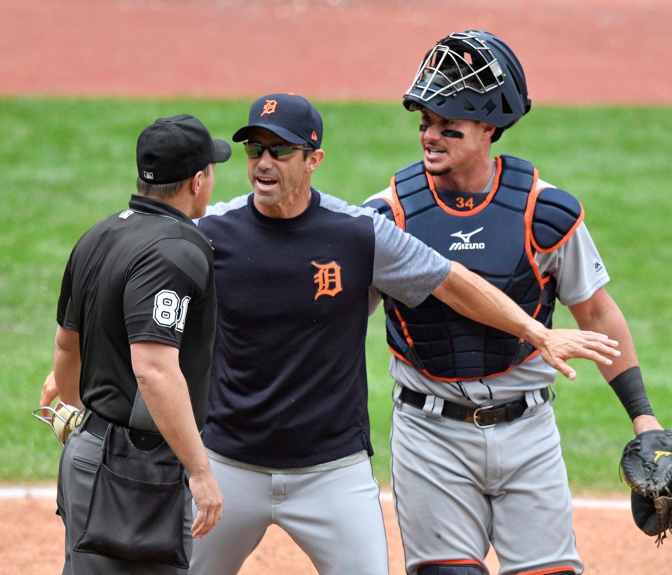 Tigers manager Brad Ausmus stands between home plate umpire Quinn Wolcott and catcher James McCann after McCann was ejected.