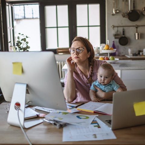 Mother working from home on desktop and laptop whi