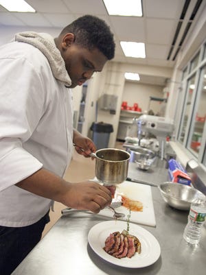 Culinary arts student Demario Clarke plates his duck dish.