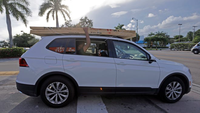 A motorist carries sheets of plywood on top of their vehicle as he leaves Home Depot in preparation for Hurricane Irma, Thursday, Sept. 7, 2017, in Miami. South Florida officials are expanding evacuation orders as Hurricane Irma approaches, telling more than a half-million people to seek safety inland.