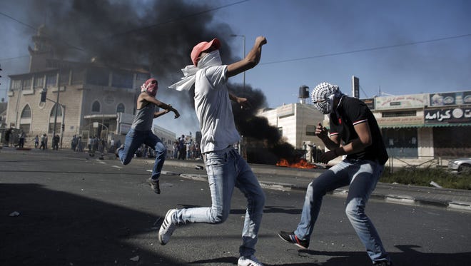 Palestinian protesters throw stones toward Israeli police during clashes in the Shuafat neighborhood in Israeli-annexed Arab East Jerusalem on July 2.