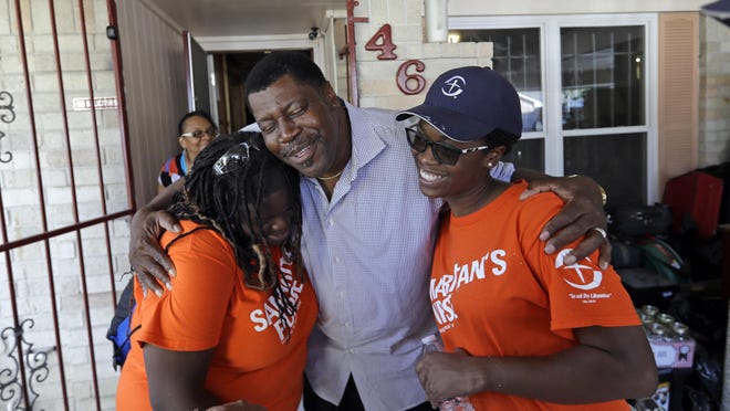 In this Nov. 17, 2017 photo, George Dorsey, center, hugs Samaritan's Purse volunteers, Nikki Moore, left, and Samantha Roundtree, who are helping rebuild his hurricane-damaged home in Houston. Dorsey usually hosts a large Thanksgiving dinner for family but is making other arrangements this year as they continue to recover from the storm damage.