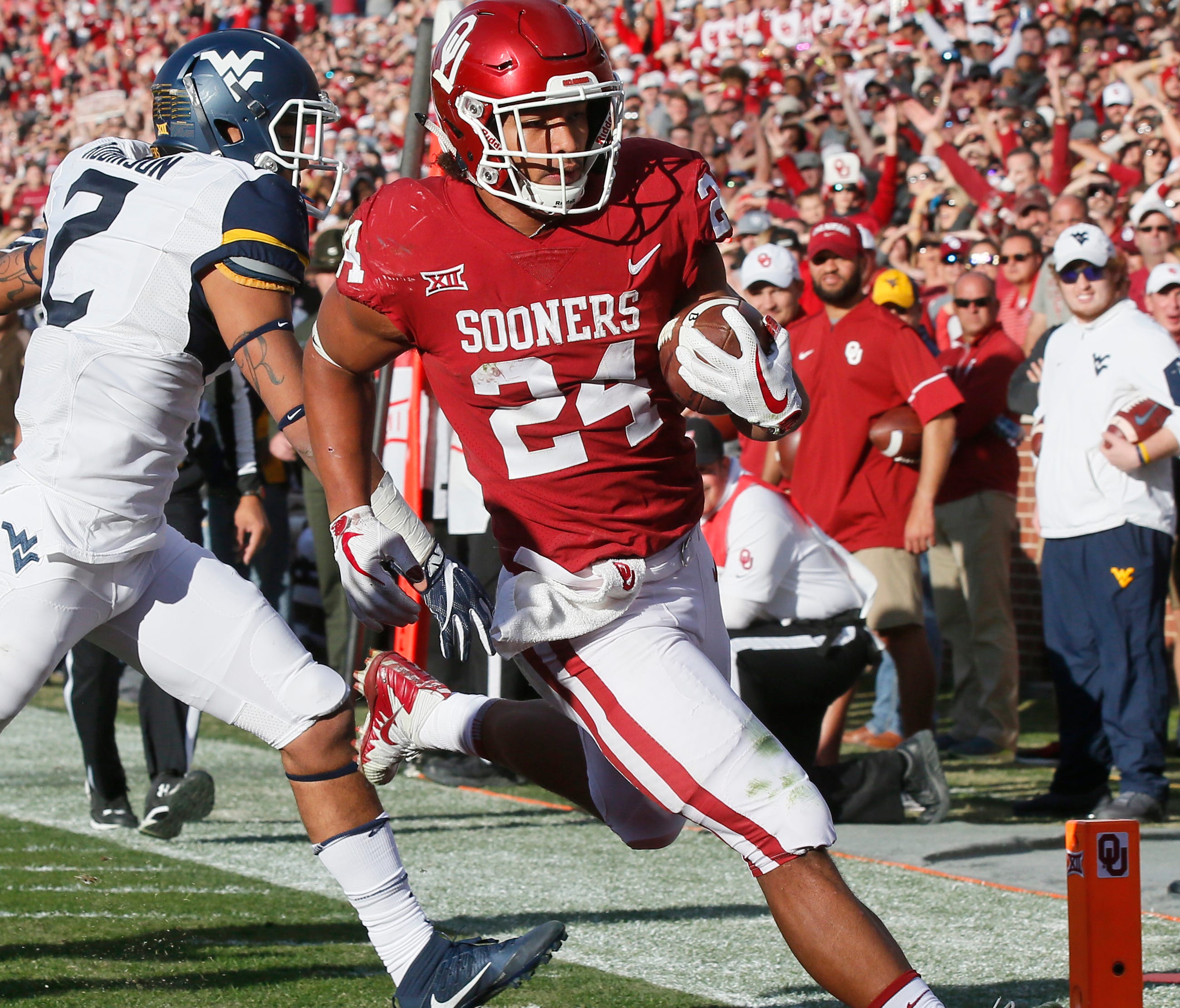 Oklahoma running back Rodney Anderson (24) scores in front of West Virginia safety Kenny Robinson (2) in the first quarter of an NCAA college football game in Norman, Okla., Saturday, Nov. 25, 2017. (AP Photo/Sue Ogrocki)