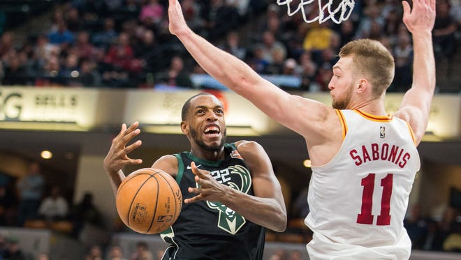 Bucks forward Khris Middleton loses the ball while driving against Pacers center Domantas Sabonis in the first half.