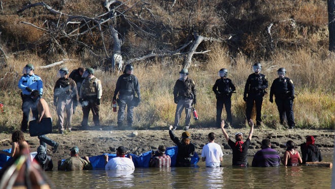 Dozens of protestors demonstrating against the expansion of the Dakota Access Pipeline wade in cold creek waters confronting local police, as remnants of pepper spray waft over the crowd near Cannon Ball, N.D., Wednesday, Nov. 2, 2016. Officers in riot gear clashed again Wednesday with protesters near the Dakota Access pipeline, hitting several dozen with pepper spray as they waded through waist-deep water in an attempt to reach property owned by the pipeline's developer. (AP Photo/John L. Mone)