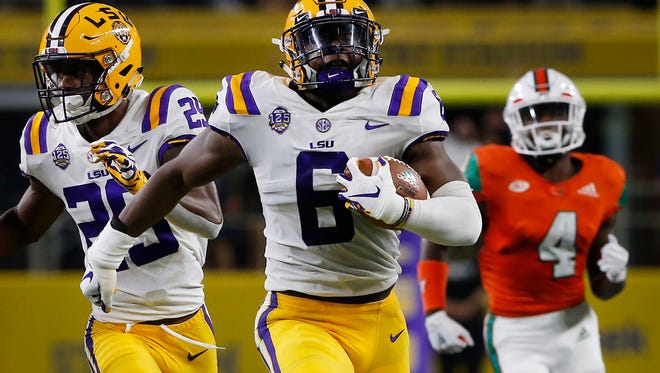 LSU linebacker Jacob Phillips (6) returns an interception for a touchdown as Miami wide receiver Jeff Thomas (4) and LSU cornerback Greedy Williams (29) look on during the first half of an NCAA college football game Sunday, Sept. 2, 2018, in Arlington, Texas. (AP Photo/Ron Jenkins)