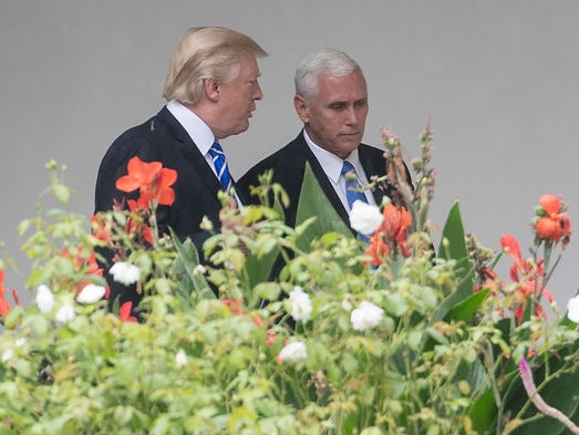 Trump speaks with Pence as they walk through the colonnade