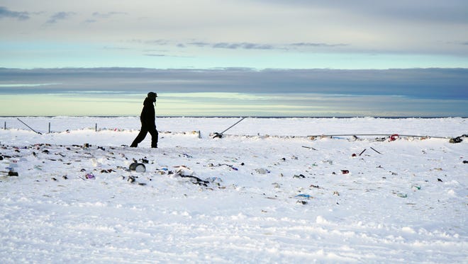 A polar bear patroller searches for signs of polar bears in the town dump outside Wales, Alaska. Climate change experts say faster-melting sea ice is causing polar bears to move onto land and seek out new food sources, like garbage.