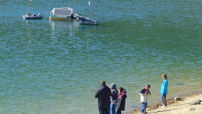 A family enjoys Grindstone Reservoir, which is fed by the snow pack runoff from the mountains into the Rio Ruidoso. The solar aerator at rop left balances the oxygen in the water and helps maintain quality.