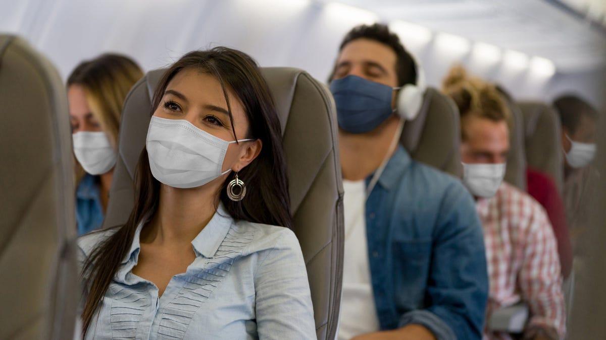 A woman wears a face mask while traveling on an airline during the COVID-19 pandemic.