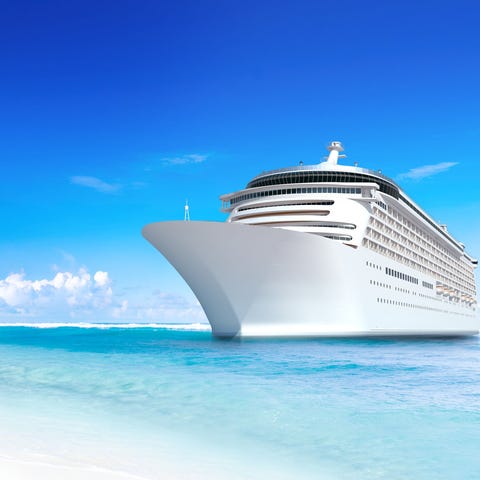 Cruise ship anchored near a beach on a sunny day.