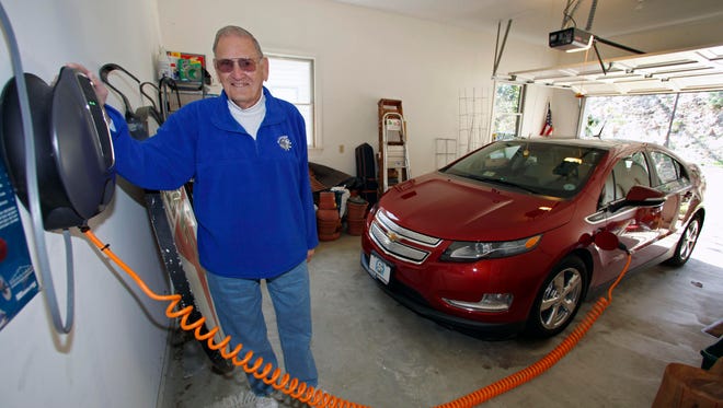 James Brazell poses with a charging unit for his Chevy Volt electric car at his home in Asheville, N.C. in this 2011 file photo