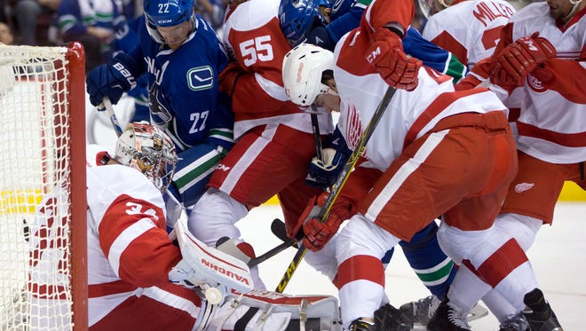 Red Wings goalie Petr Mrazek, bottom left,  makes the save as the Canucks' Daniel Sedin (22) and Radim Vrbata, back center, dig for the puck while Niklas Kronwall (55), Alexei Marchenko, front center, Drew Miller and Luke Glendening, right, defend during the first period of 
Saturday in Vancouver.